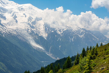 Picturesque panoramic view of the snowy Alps mountains, the Mont Blanc mountain and glacier and meadows while hiking Tour du Mont Blanc. Popular hiking route. Alps, Chamonix-Mont-Blanc region, France