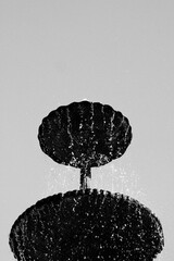 A simple fountain bowl with water dripping from the top in black and white.