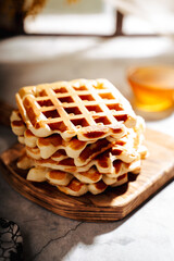 Belgian waffles on a wooden board on the table, spring atmosphere,
