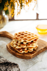 Belgian waffles on a wooden board on the table, spring atmosphere,	

