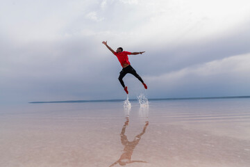 Portrait of african american man jumping over sea. happy man jumping in the sea