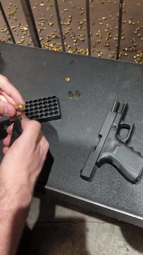 gros plan sur les mains du personne remplissant de balles, un chargeur de pistolet 