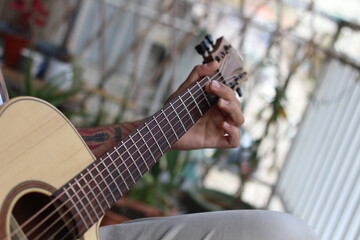 Melodic Reverie: Young Tattooed Musician Playing Acoustic Guitar on Balcony
