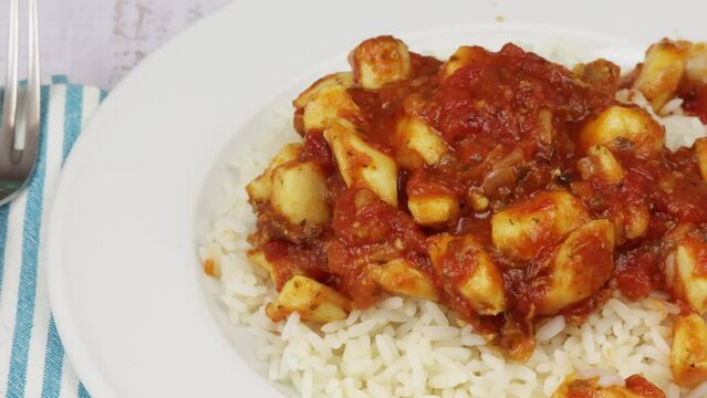 calamars, sauce tomate cuisin&eacute; et riz dans une assiette