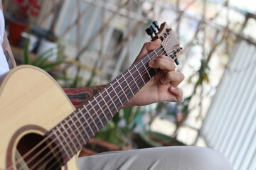 Melodic Reverie: Young Tattooed Musician Playing Acoustic Guitar on Balcony