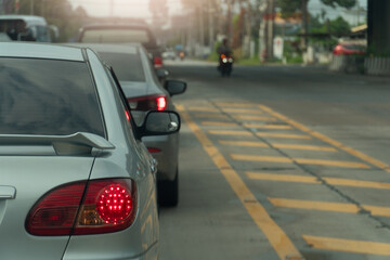Rear side of car with turn on brake light. Traffic jam on the asphalt road with yellow line and bokeh light background.