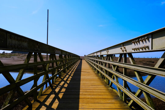Pedestrian bridge leading to sea shore sand beach outdoors scenic landscape photo.