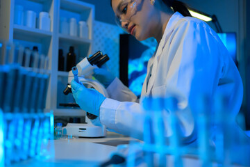 A woman in a lab coat is holding a microscope slide