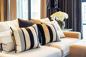A photo of black and white striped pillows on the beige sofa in modern living room with big window