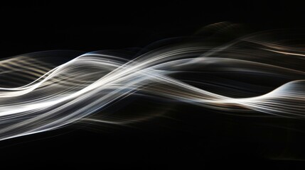 Long exposure photograph of white light waves on a black background, with streaks of light in the...