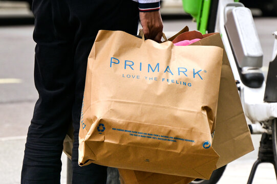 London, England, UK - 24 August 2023: Person carrying a large brown paper bag after purchasing clothes from Primark in central London