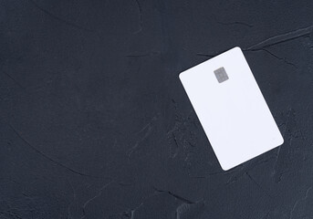 White credit card on a blank black background, top view. Copy space