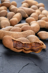 Scattered tamarind fruits in shell on dark background