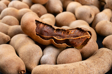 Pile of fresh tamarind fruits in shell close up