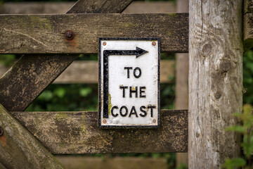 Sign: To the beach, screwed to a wooden fence