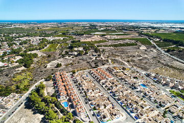 Drone point of view countryside meadows and Pinar de Campoverde residential district view with modern new-built houses, villas view from above. Summer day. Costa Blanca, Province of Alicante, Spain
