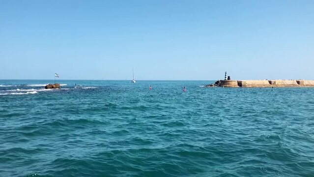 Lighthouse Marina of Old Jaffa. Andromeda stones and the flag of Israel. Mediterranean sea, concept of travel to the holy land, sailing. Slow motion.