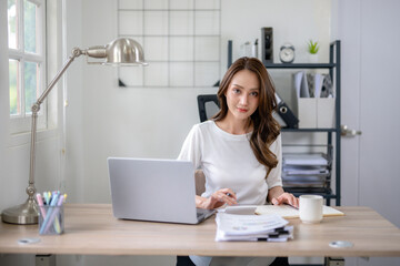 Confident female entrepreneur calculates and analyzes documents while working from home office.