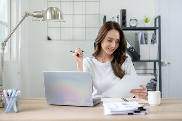 Confident female entrepreneur calculates and analyzes documents while working from home office.