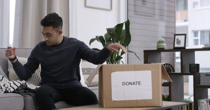 Home, man and donation of clothes in box, charity organisation and packing for giving with kindness. Person, humanity support and sorting of clothing in spring cleaning, living room and non profit