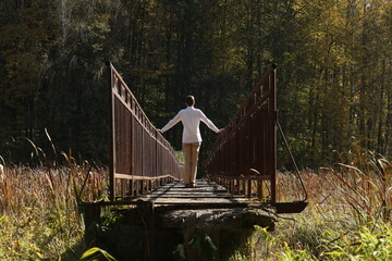 Young man in white shirt walking on the narrow bridge. Photo was taken 24 September 2023 year. - 766450882