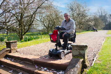 No access-disabled man on his mobility scooter sits looking down steps that he cannot access. whilst out enjoying the freedom his vehicle allows him. 