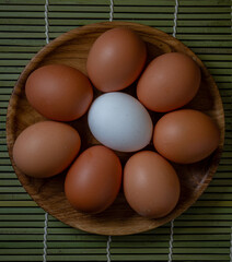 Fresh chicken eggs in wooden plate on the table, selective focus