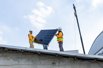 Technicians Install photovoltaic solar modules on roof of factory. Engineers install or fix solar cells in roof of factory. Technician worker on solar panels. Solar technician working on factory roof