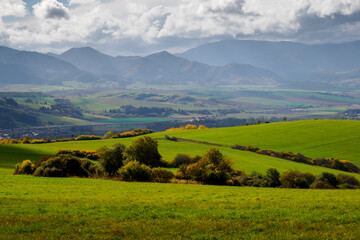 Mountain landscape. In the foreground, a farmland and autumn trees. In the distance you can see the...