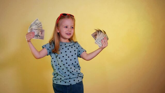 A little girl gleefully holding a handful of cash. Smiling child proudly displaying a stack of money. Excited girl showing off her money stack. Happy kid with a stack of cash in hand. The little girl 