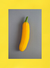 Yellow zucchini on the gray and yellow background. Close-up.
