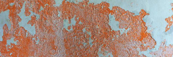 Panoramic image. Orange plaster peeling off an old wall. Old dirty peeling plaster wall. Texture,...