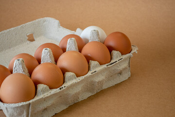 Fresh chicken eggs in a paper tray on the table, selective focus