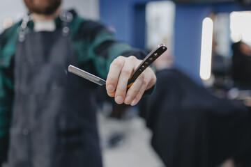 Hairdresser holds razor on background barbershop