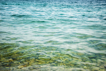 Fototapeta na wymiar Clean transparent turquoise sea water, through which you can see pebbles on the bottom of the sea