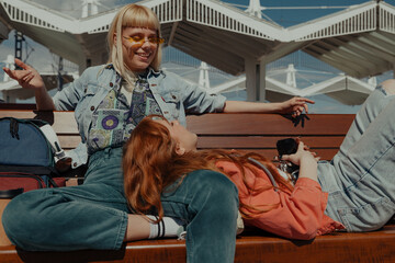 One friend lying on a bench talking to another
