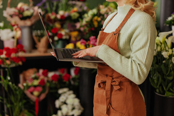 Florist using a laptop amidst blooms