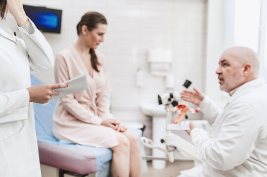 Man doctor look microscope at gynecologist's appointment, examining patient on chair with equipment. Colposcopy and Pap test. Doctor and nurse at medical appointment consultation blurred image