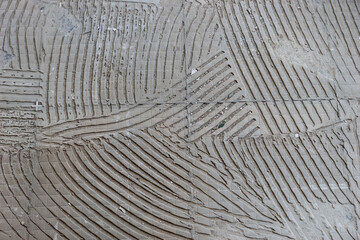 Background of old tile adhesive on the floor. Abstract pattern of notched trowel