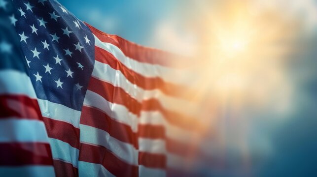 Close up of the American flag waving in the wind against a bright blue sky with a sunburst in the background