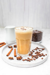 Coffee latte in glass with cinnamon, spices and roasted coffee beans. Creamy coffee with milk. Coffee drink recipe. 