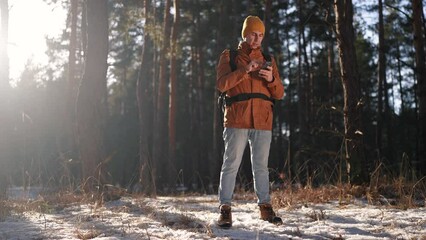 travel navigation. man tourist looking for a way in a smartphone navigation in winter in a forest park. male hacker navigates in the forest navigation looking for a way in winter in lifestyle park