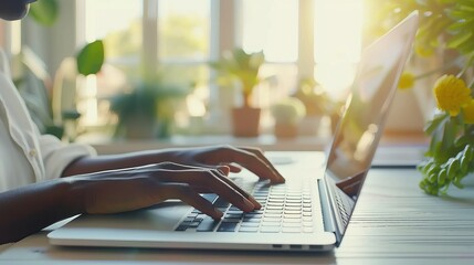 Black woman typing on a laptop in a home office