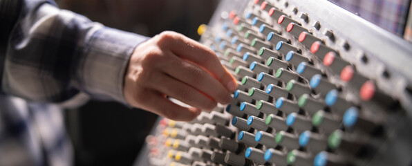 Close-Up of a Hand Adjusting the Controls on a Music Mixer Console in a Studio - 766503849