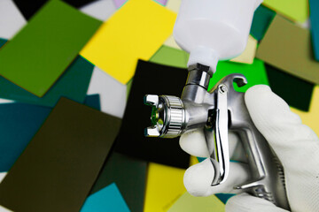 paint spray gun at work at the workplace in the workshop, selection of tools, paint samples