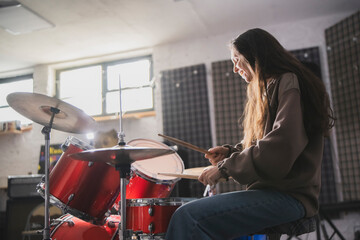 Energetic Female Drummer Enjoys Playing Red Drum Kit in a Casual Setting - 766505617
