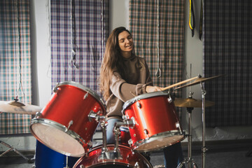 Energetic Female Drummer Enjoys Playing Red Drum Kit in a Casual Setting - 766506027