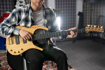 Young Musician Playing the Bass Guitar in a Rehearsal Studio Setting - 766506212