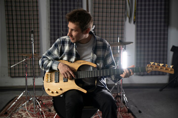 Young Musician Playing the Bass Guitar in a Rehearsal Studio Setting - 766506255