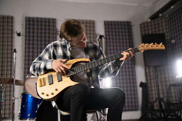 Young Musician Playing the Bass Guitar in a Rehearsal Studio Setting - 766506265